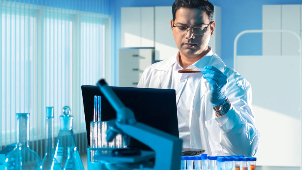 A lab technician inputting test sample data into a LIMS on a laptop computer - Which LIMS is the best in 2025?
