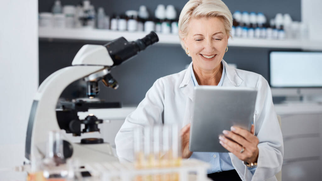 A woman using a LIMS on her tablet within a laboratory - Find the best LIMS in 2025