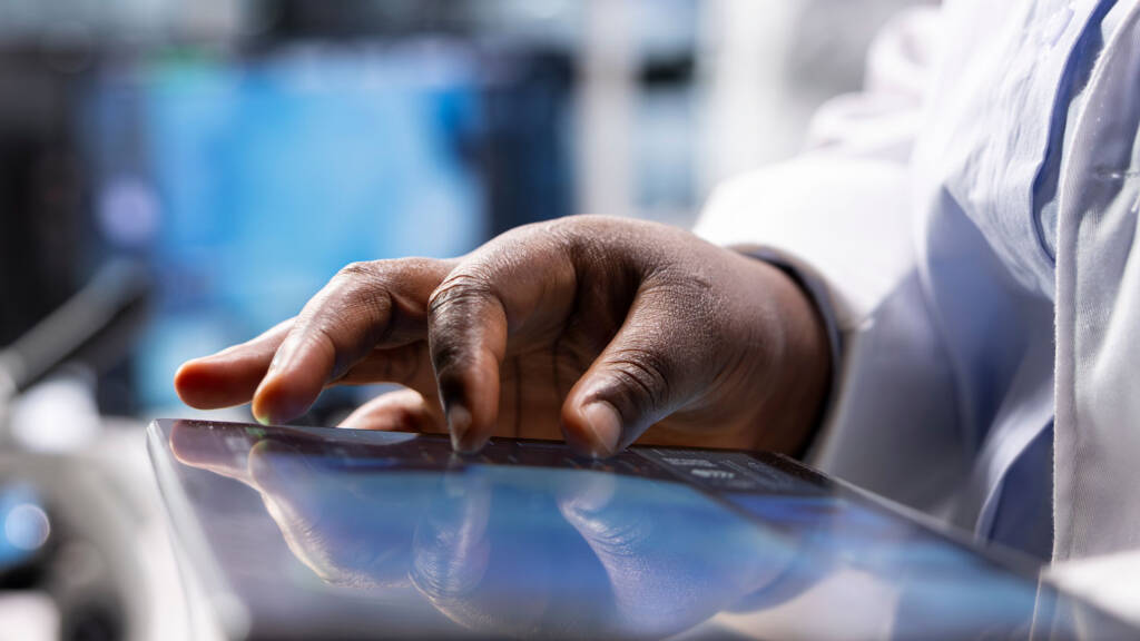 Close-up of lab worker using tablet for data entry, representing digital lab workflows and future-ready LIMS technology